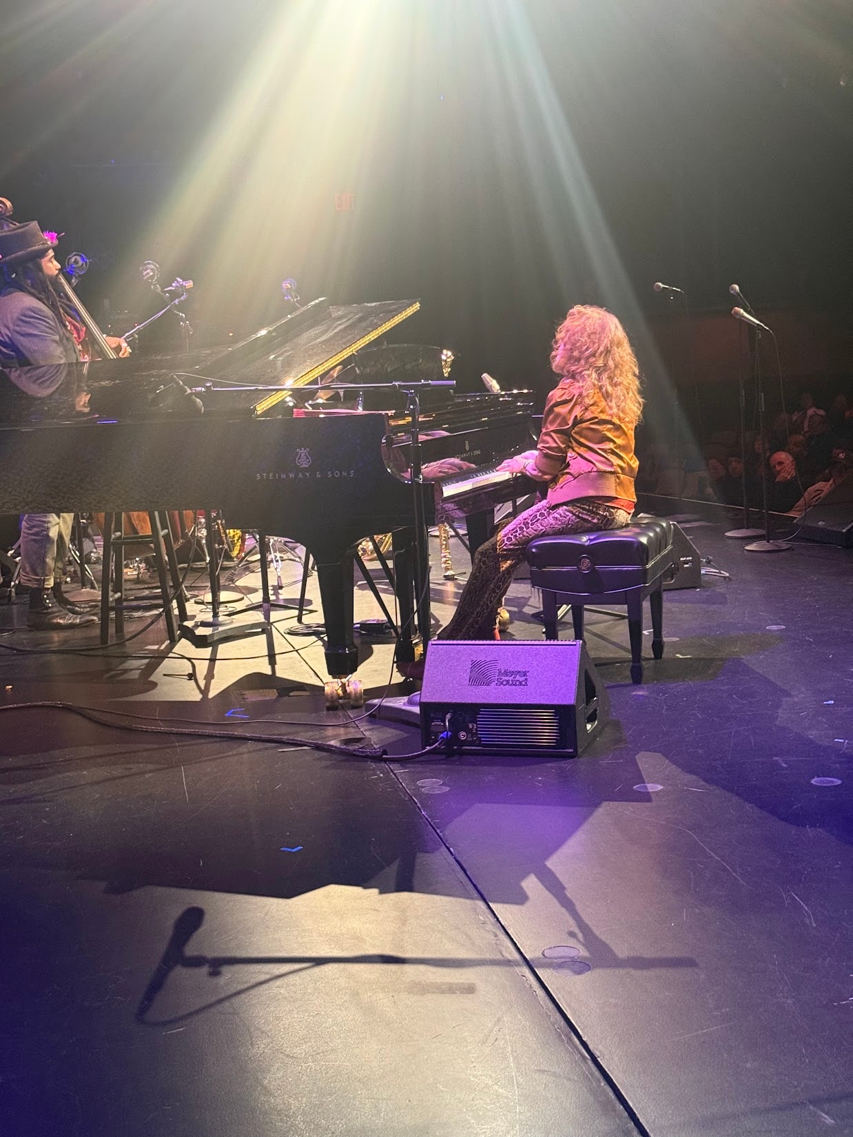 Pianist performing on Steinway grand piano at concert with dramatic stage lighting